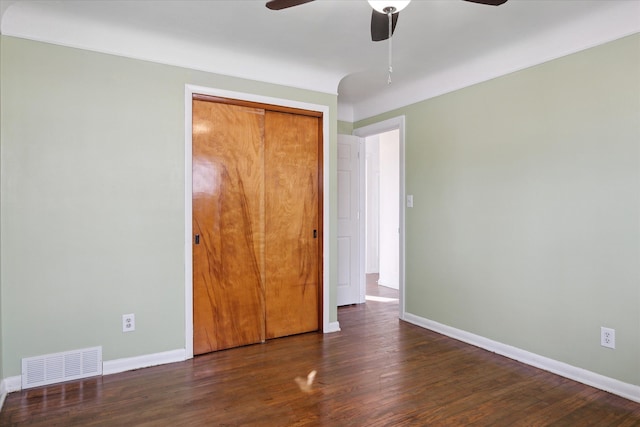 unfurnished bedroom featuring dark wood-type flooring, a closet, and ceiling fan