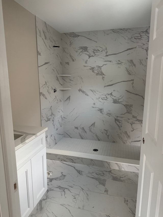 bathroom with tiled shower and vanity