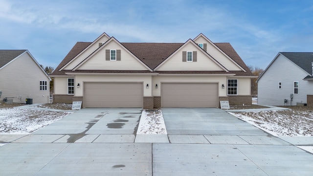 view of front facade with an attached garage, central AC unit, concrete driveway, and brick siding