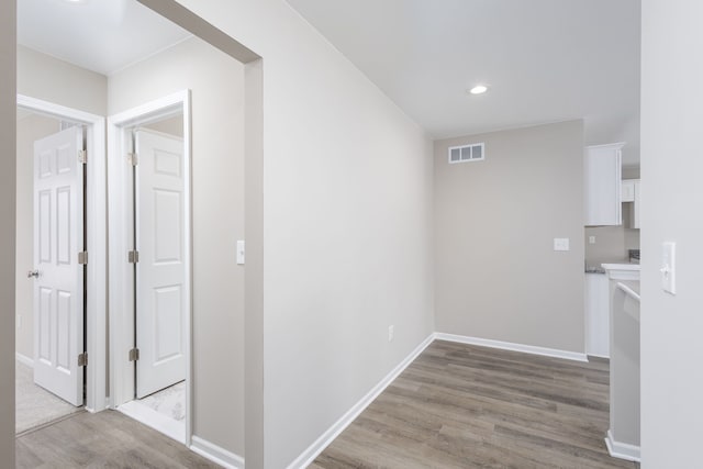 hall featuring light wood-style floors, recessed lighting, visible vents, and baseboards