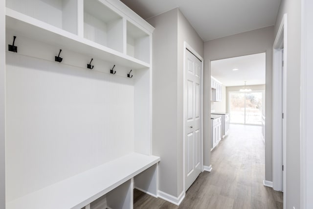 mudroom with dark wood-style floors, baseboards, and a chandelier