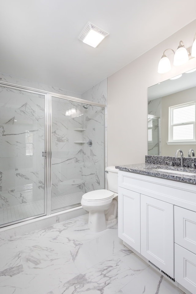 full bath with toilet, marble finish floor, a marble finish shower, and vanity