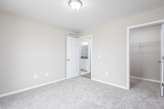 unfurnished bedroom with carpet floors, visible vents, a spacious closet, and baseboards