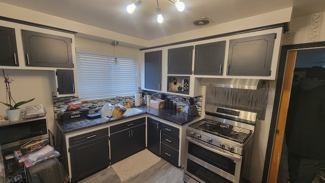 kitchen with extractor fan, decorative light fixtures, light hardwood / wood-style floors, and range with two ovens