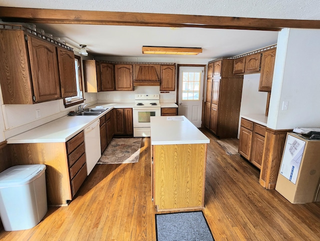 kitchen featuring white appliances, a kitchen island, dark wood finished floors, beam ceiling, and a sink