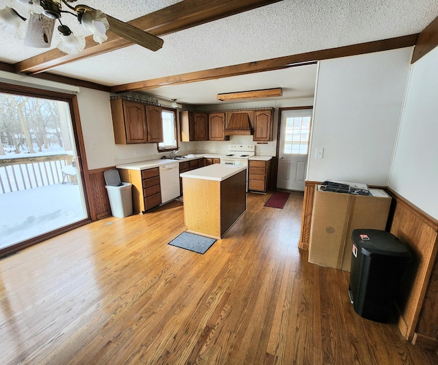 kitchen featuring a wainscoted wall, white appliances, and beamed ceiling