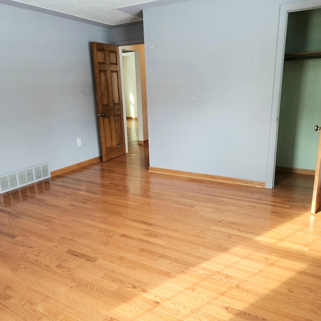 unfurnished bedroom with a spacious closet, baseboards, visible vents, and light wood-type flooring