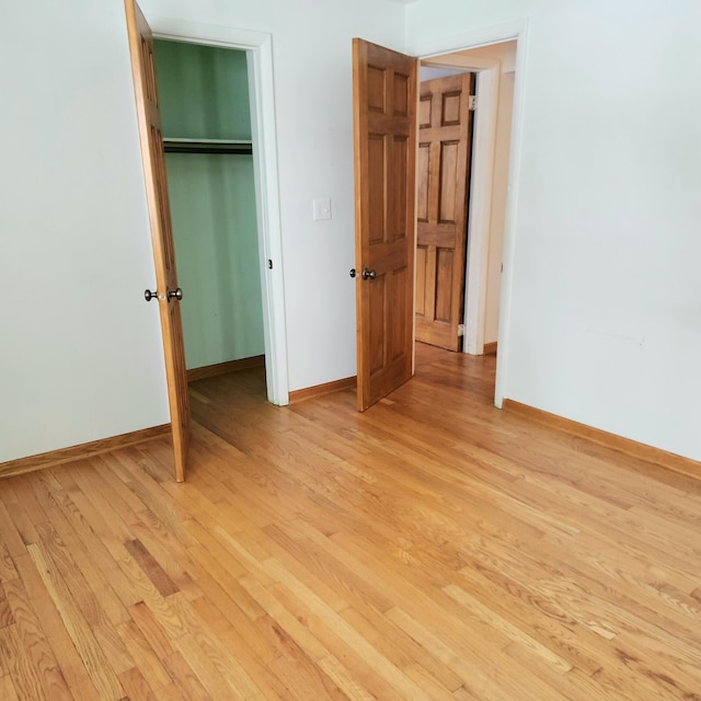 unfurnished bedroom featuring a closet, baseboards, and light wood finished floors