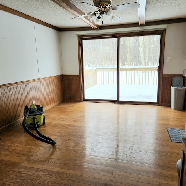 unfurnished room featuring a wainscoted wall, a textured ceiling, and wood finished floors