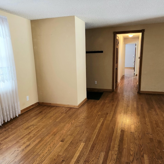 unfurnished room featuring wood finished floors, baseboards, and a textured ceiling