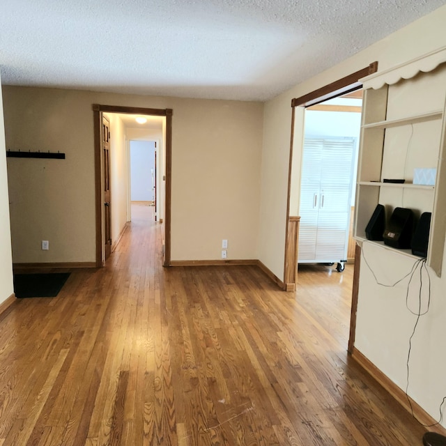 unfurnished room featuring baseboards, wood-type flooring, and a textured ceiling