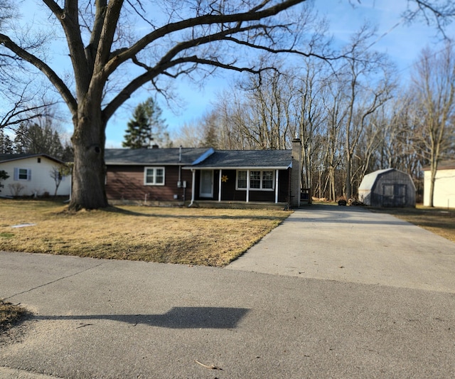 view of front of home with an outbuilding, a porch, a chimney, and a front yard