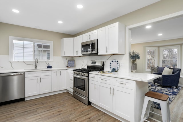 kitchen with backsplash, sink, white cabinets, and appliances with stainless steel finishes