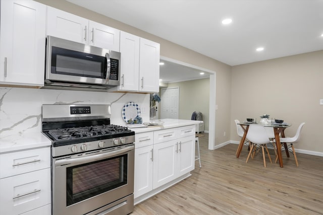 kitchen featuring white cabinetry, stainless steel appliances, light stone countertops, and light hardwood / wood-style flooring