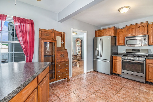 kitchen with beamed ceiling, ceiling fan, stainless steel appliances, and light tile patterned floors