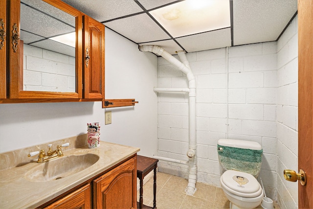 bathroom with vanity, tile patterned flooring, toilet, and a drop ceiling