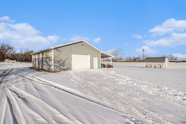 snow covered property with an outbuilding and a garage