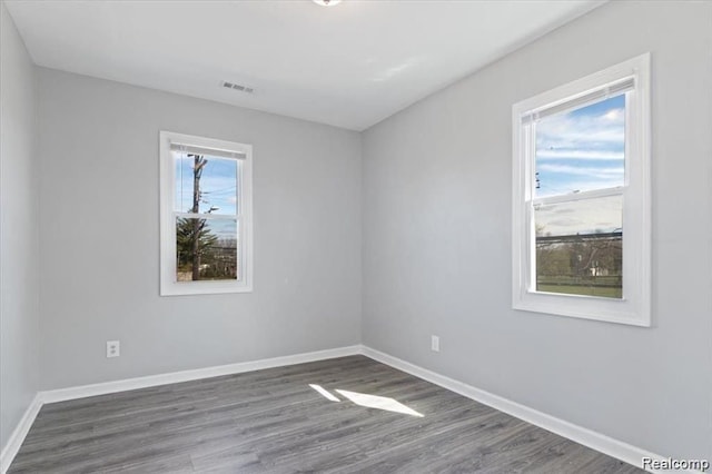 unfurnished room featuring dark hardwood / wood-style flooring and a wealth of natural light