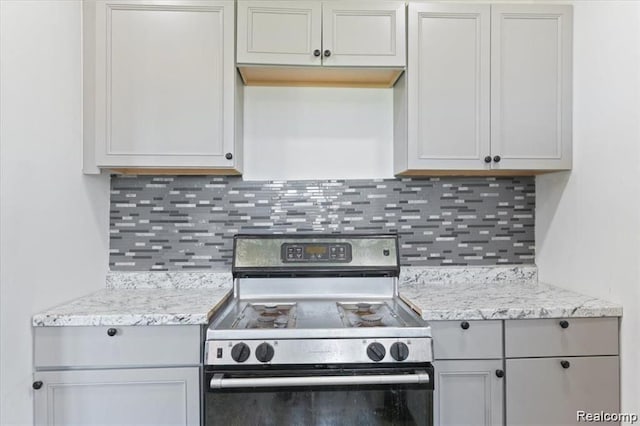 kitchen featuring light stone countertops, stainless steel range with gas cooktop, and decorative backsplash