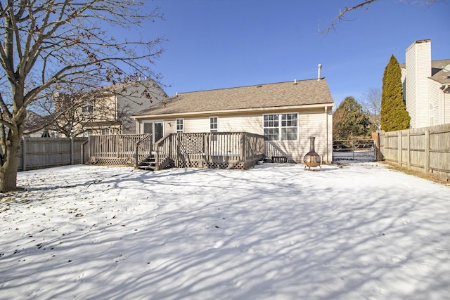 snow covered rear of property with a deck