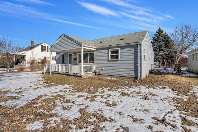 snow covered rear of property with covered porch