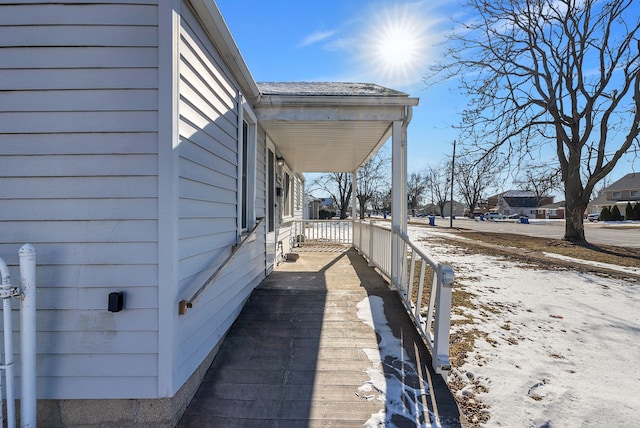 snow covered property with covered porch