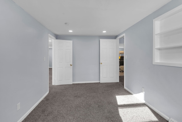 spare room featuring dark carpet and built in features