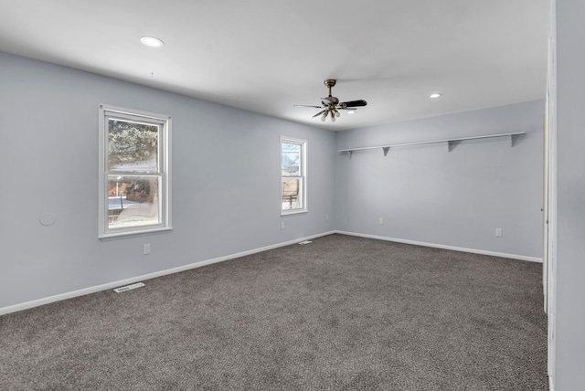 empty room with dark colored carpet and ceiling fan