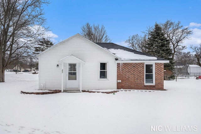 snow covered rear of property featuring a trampoline