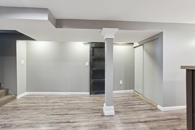 basement with light hardwood / wood-style floors and a barn door