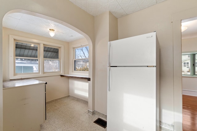 626 Orange St, Jackson, MI 49202 - kitchen with freestanding refrigerator, healthy amount of natural light, baseboards, and arched walkways