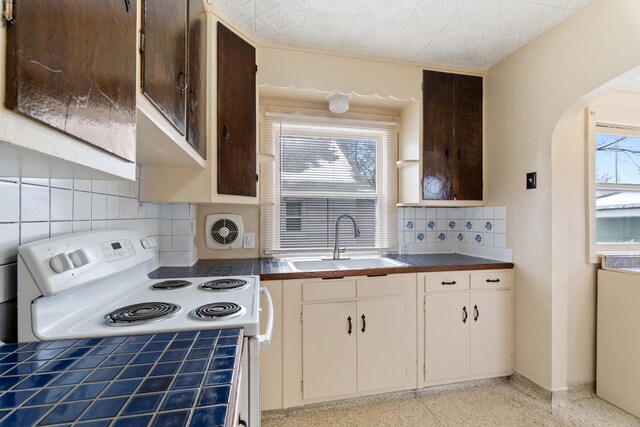 626 Orange St, Jackson, MI 49202 - kitchen with a sink, white range with electric stovetop, dark speckled floor, arched walkways, and decorative backsplash