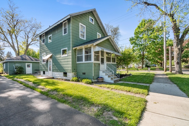 626 Orange St, Jackson, MI 49202 - view of front of house with entry steps, a front yard, and a sunroom