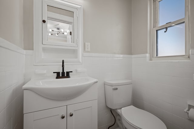 bathroom featuring vanity, toilet, and tile walls