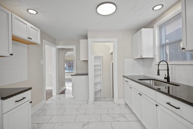 kitchen with tasteful backsplash, sink, dark stone counters, and white cabinets