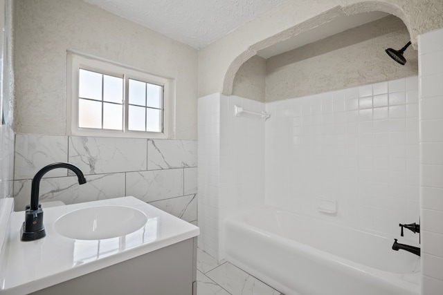 bathroom featuring shower / bathing tub combination, vanity, tile walls, and a textured ceiling