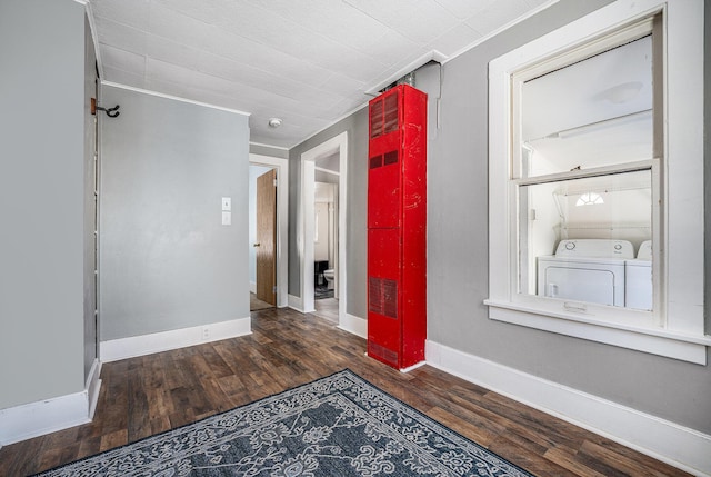 corridor with dark wood-type flooring, independent washer and dryer, and crown molding