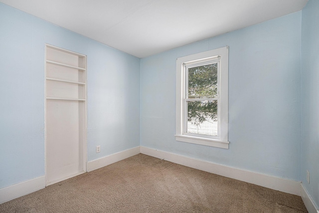 carpeted empty room featuring built in shelves