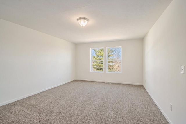 empty room featuring light carpet and baseboards