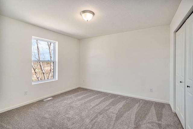 unfurnished bedroom with a closet, carpet, visible vents, and baseboards