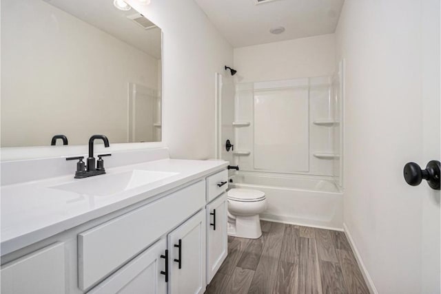 bathroom featuring shower / bathing tub combination, toilet, vanity, wood finished floors, and baseboards