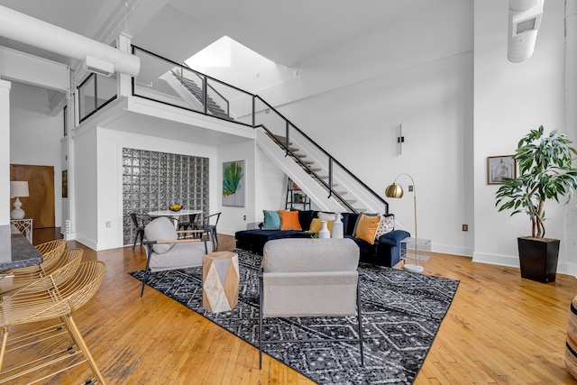 living room featuring hardwood / wood-style flooring, a skylight, and a high ceiling