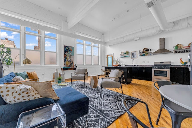 living room with hardwood / wood-style flooring, sink, and beamed ceiling