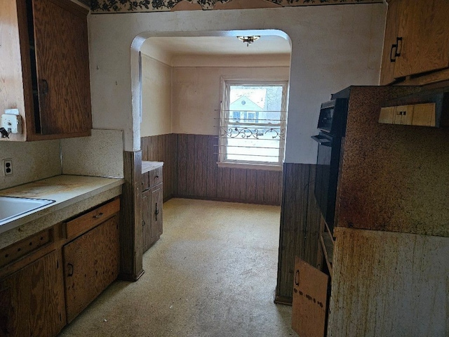 kitchen with oven, sink, and wood walls