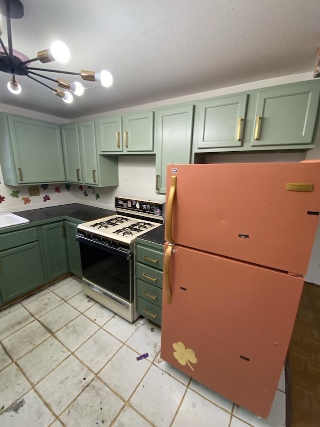 kitchen with sink, white range with gas stovetop, green cabinetry, a textured ceiling, and fridge