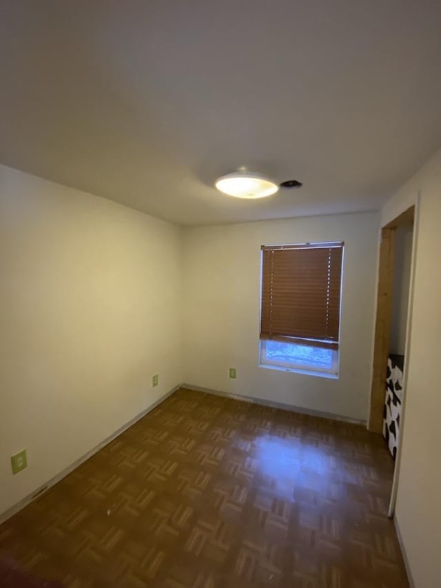 spare room featuring dark parquet flooring