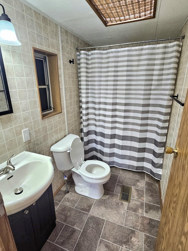 bathroom featuring tile walls, vanity, and toilet