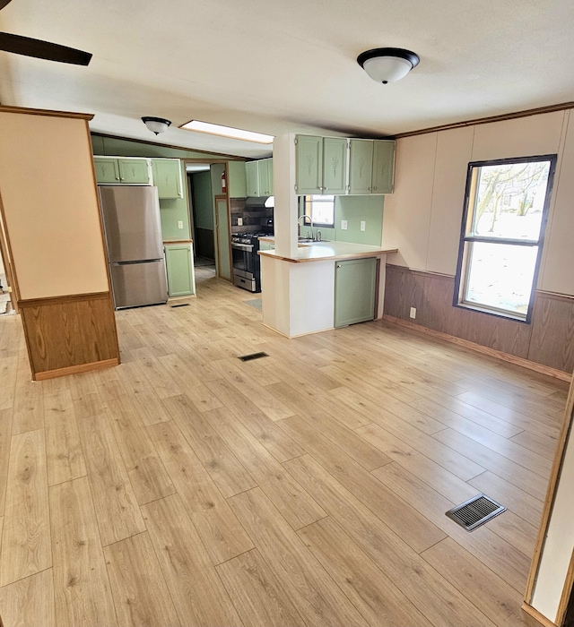 kitchen featuring stainless steel appliances, light wood-type flooring, and green cabinetry