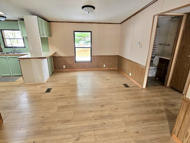 interior space featuring crown molding, sink, light wood-type flooring, and green cabinetry