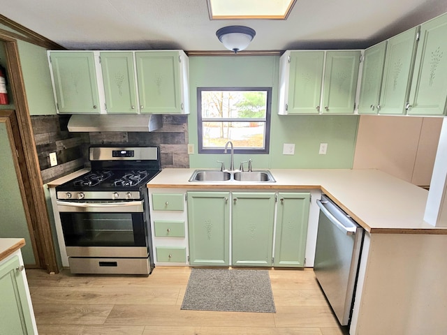 kitchen with stainless steel appliances, sink, green cabinets, and backsplash